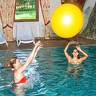 Hotelfotograf fotografiert Hotelgäste beim Wasserballspiel im Schwimmbad Wellness Hotel